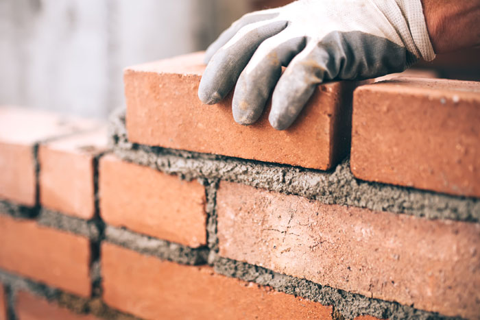 close up of hand laying down brick